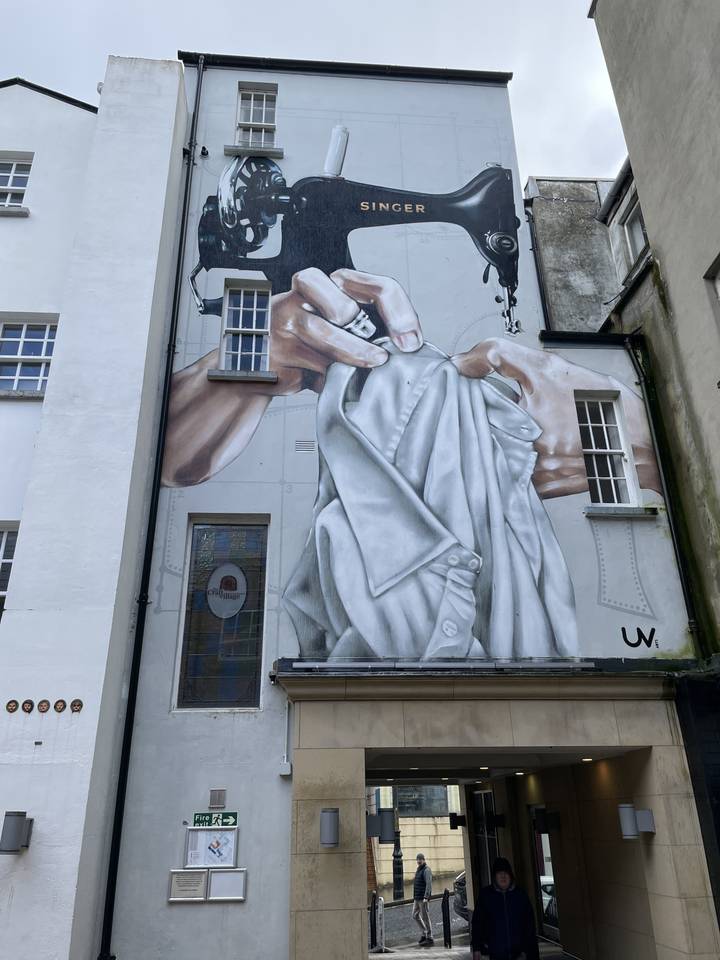 Mural of a giant hand using a sewing machine.