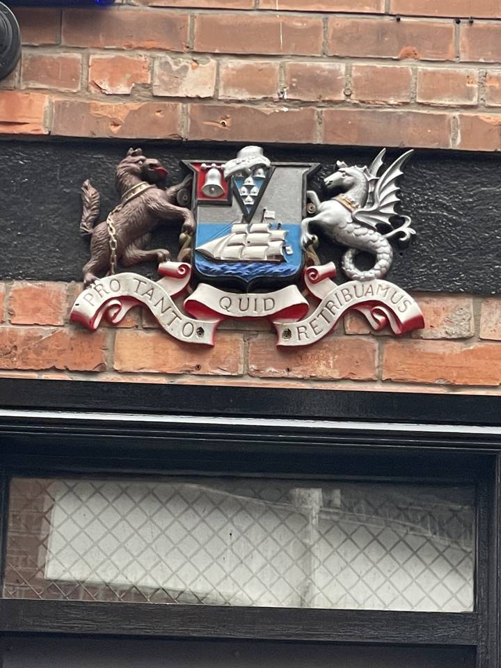 Coat of arms on a brick wall with Latin inscription.