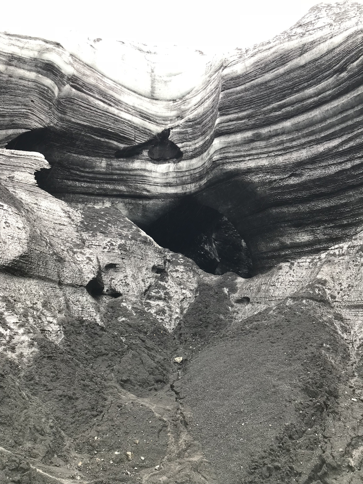 A dark cave or rock formation with layered patterns.