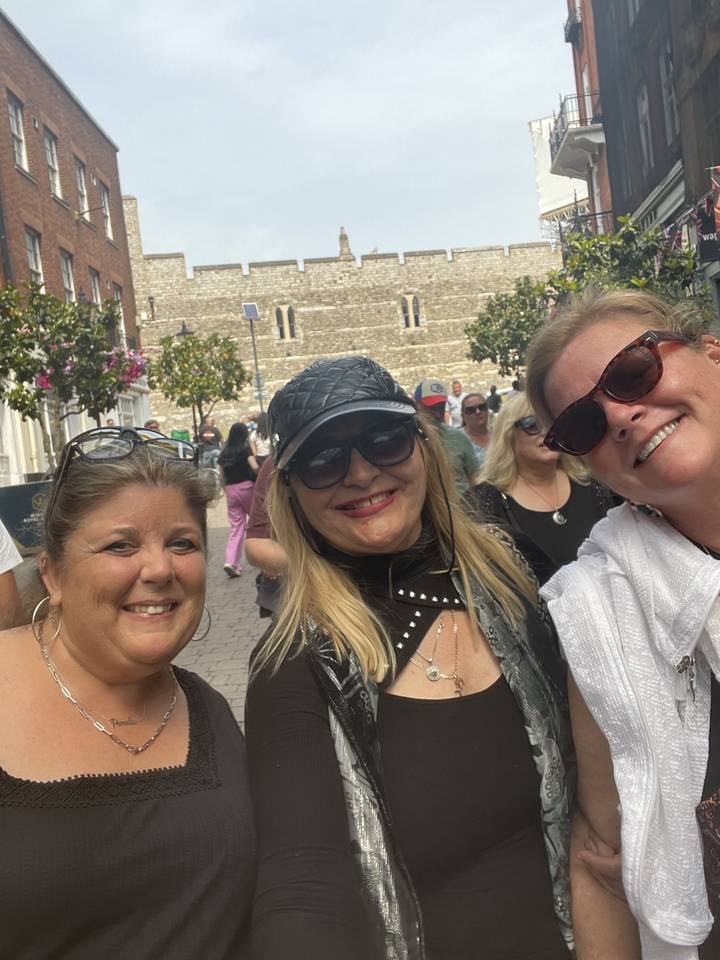 Three women posing with sunglasses in an urban environment.