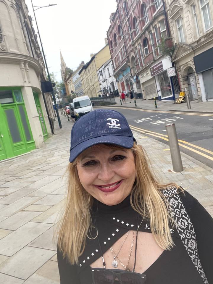 Woman in a cap posing in a city street.
