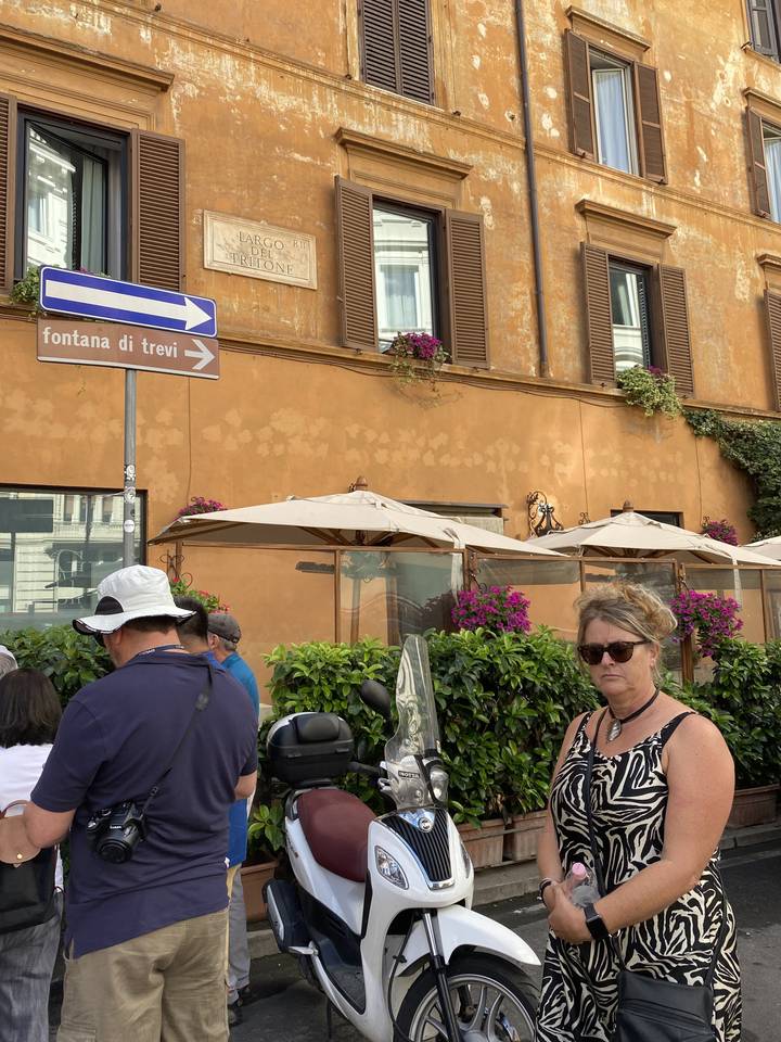 People walking past a building with a street sign.