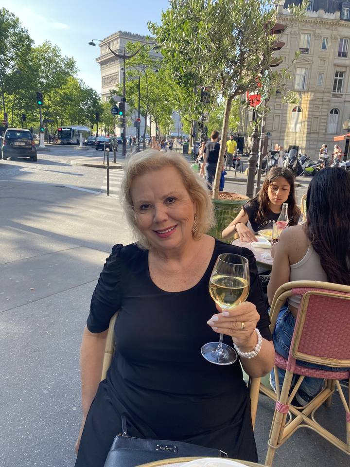 Person enjoying a drink at an outdoor cafe in a city setting.