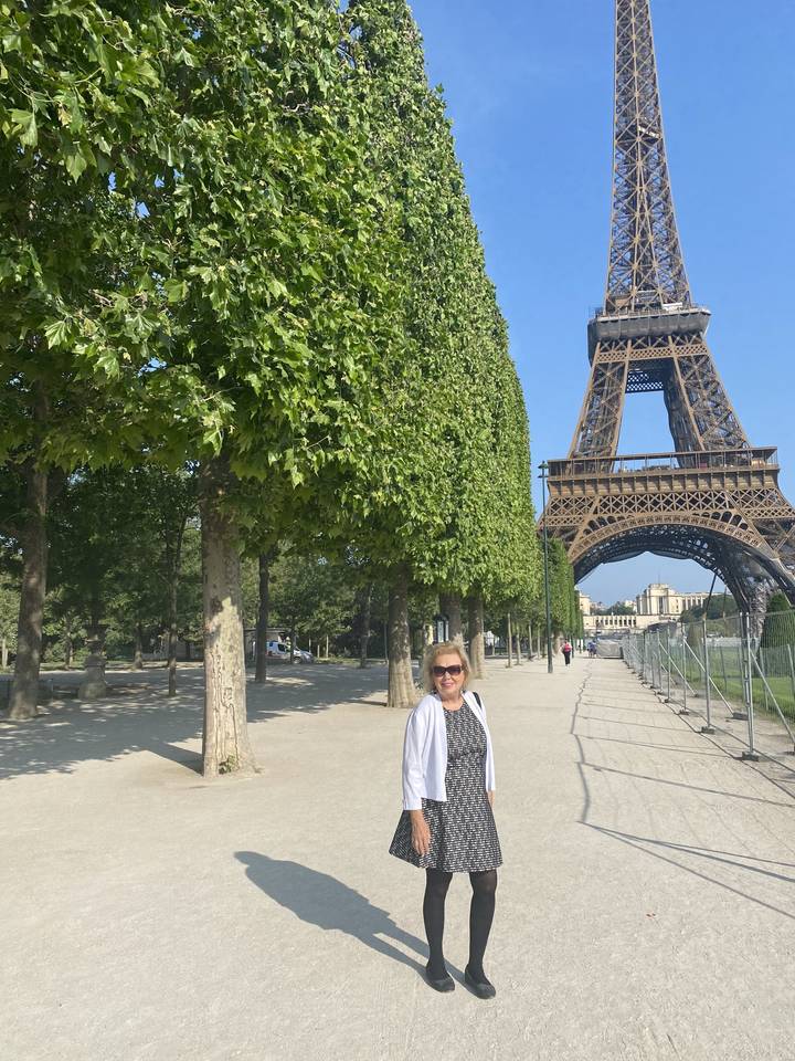 Person posing beside the Eiffel Tower.