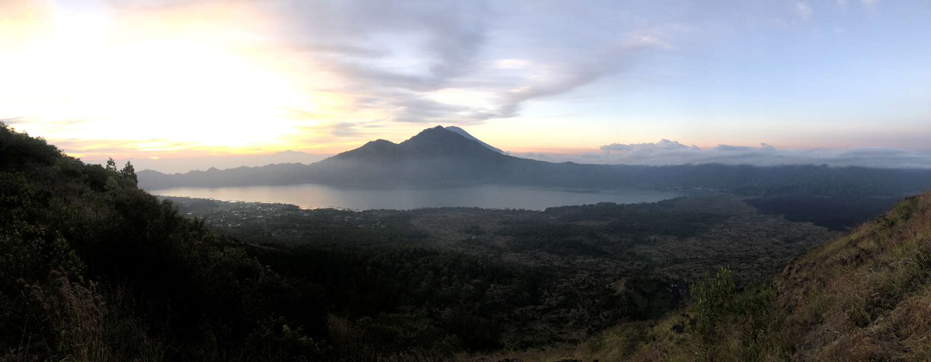 Wide view of a mountain and lake at sunset.