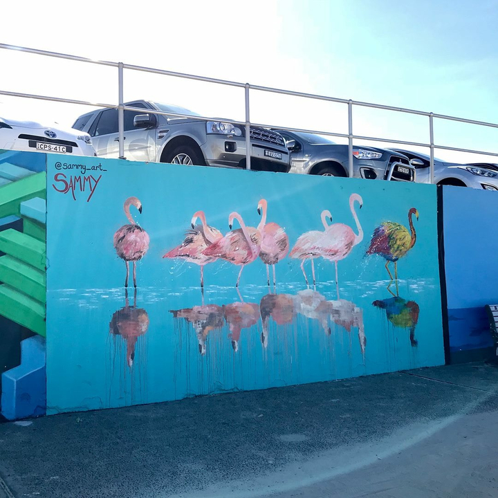 Colorful mural of flamingos on a street wall.