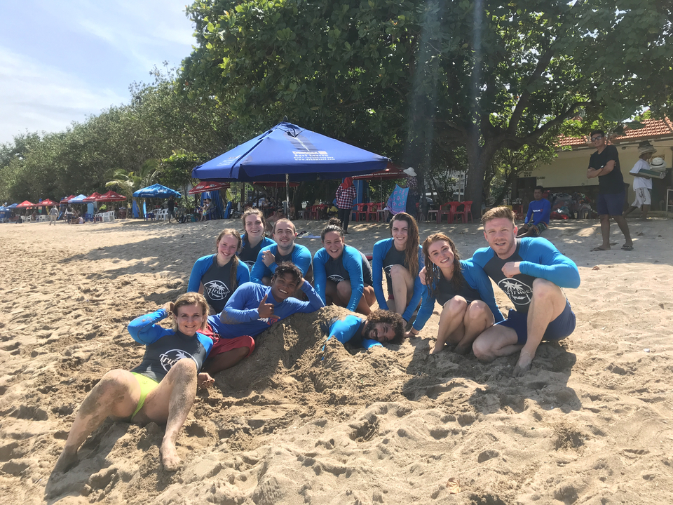 Group enjoying a day on the beach with sand and umbrellas.