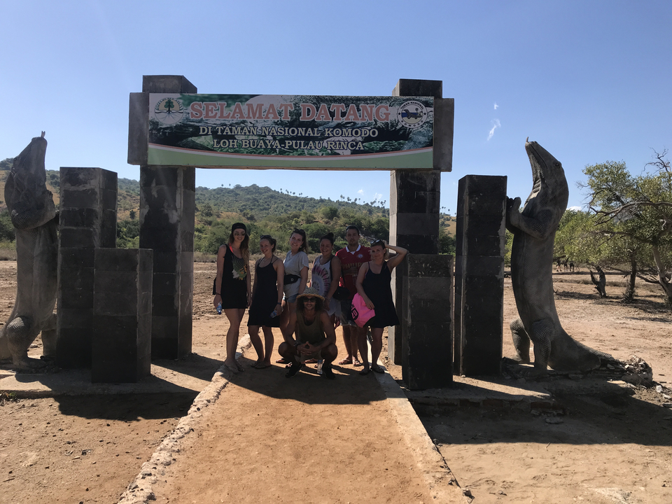 Group posing under a park entrance with Komodo dragons.