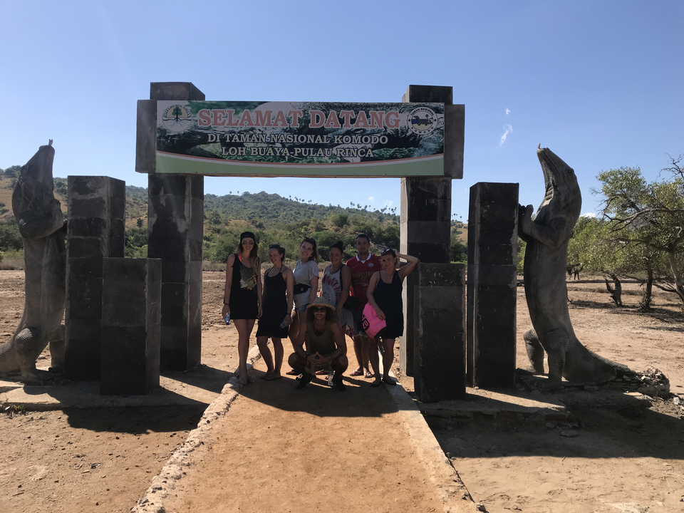 Group posing under a park entrance with Komodo dragons.