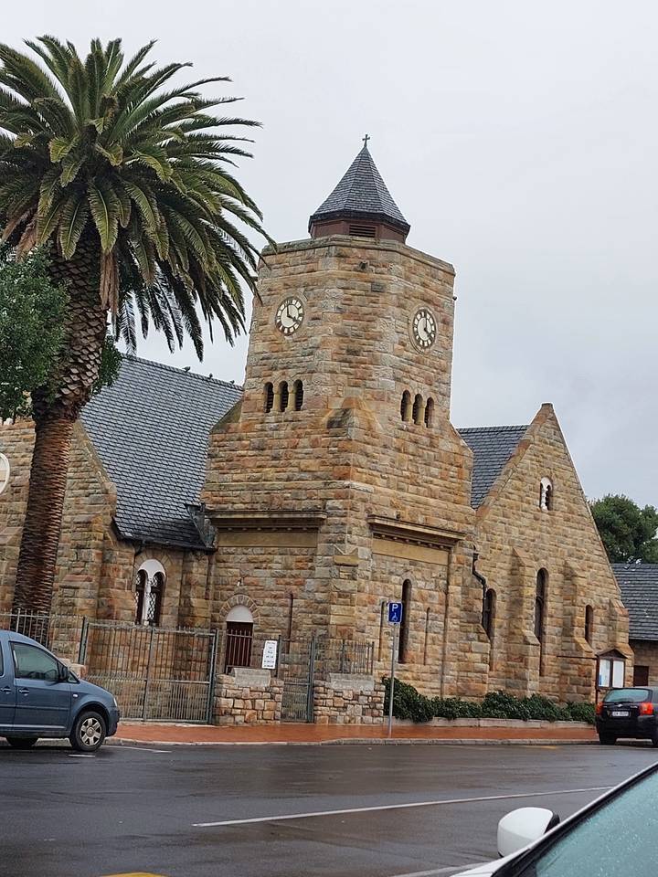 Stone church with clock tower and palm tree.
