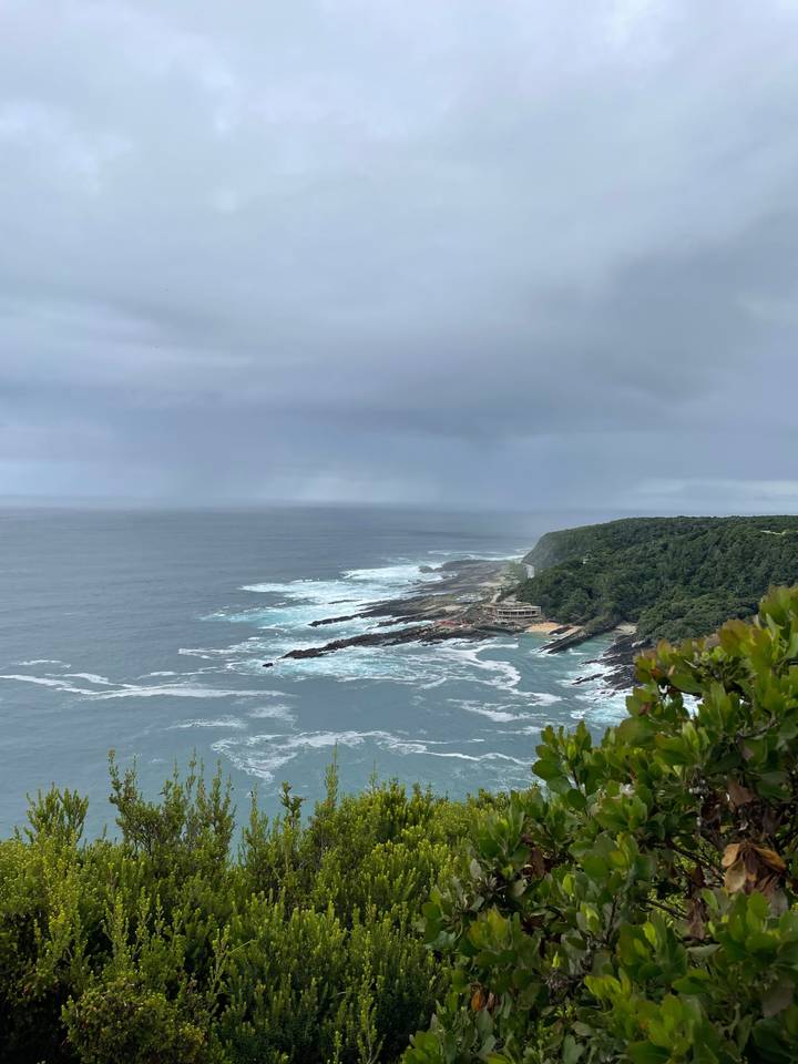 View of rocky coastline and ocean with heavy clouds above.