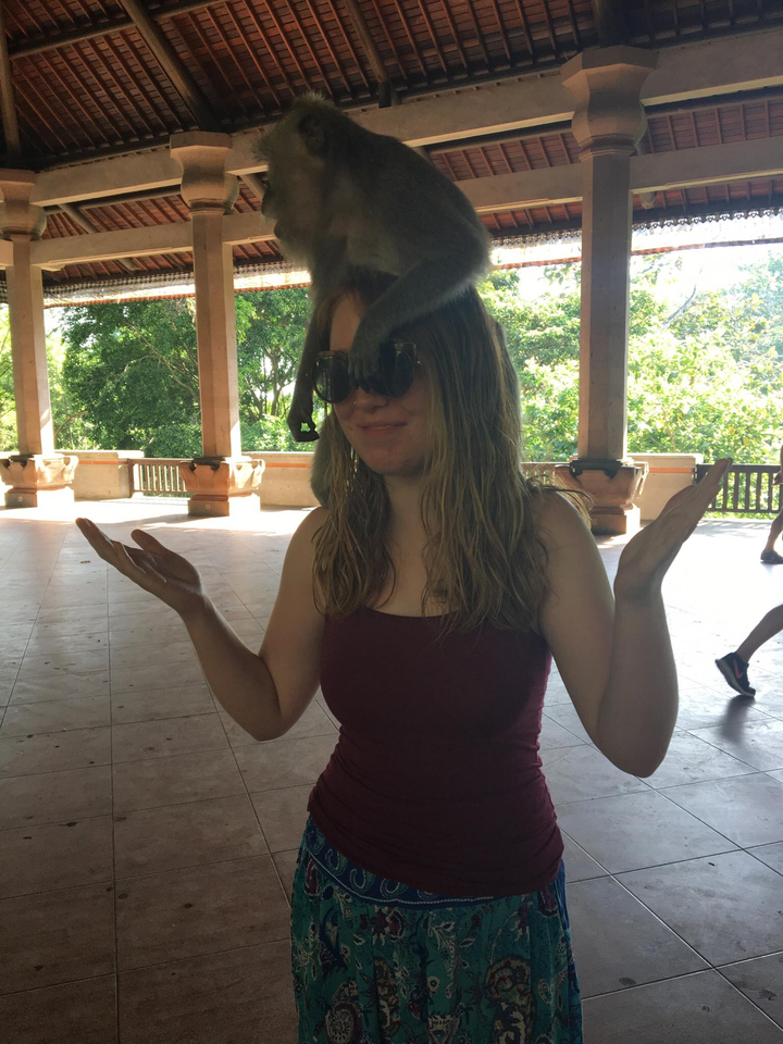Person posing with sunglasses inside a building with a forest view outside.