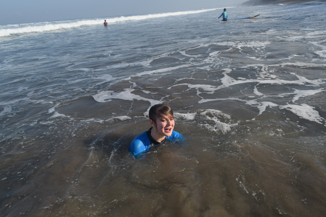 Person swimming in the ocean with waves and other swimmers in the background.