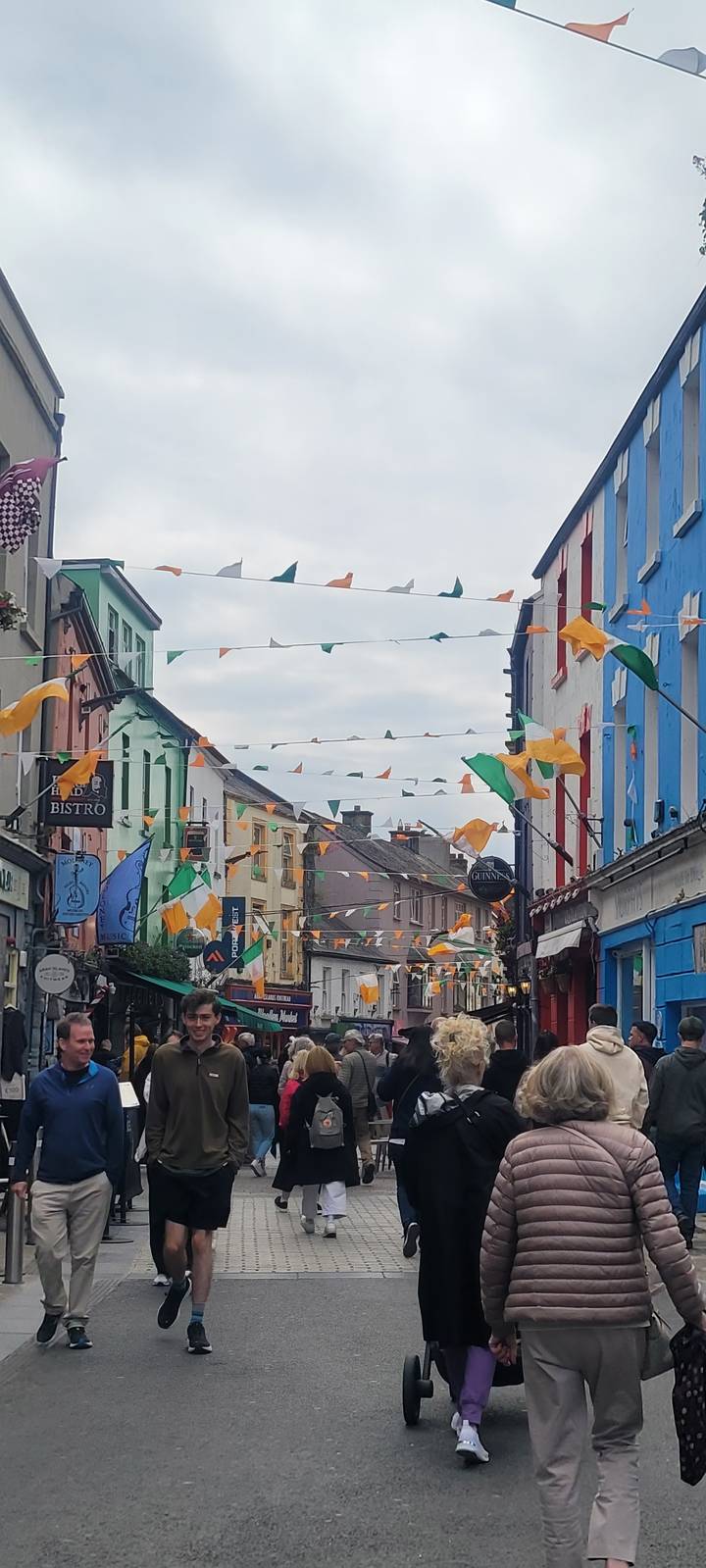Busy pedestrian street with colorful bunting and people.