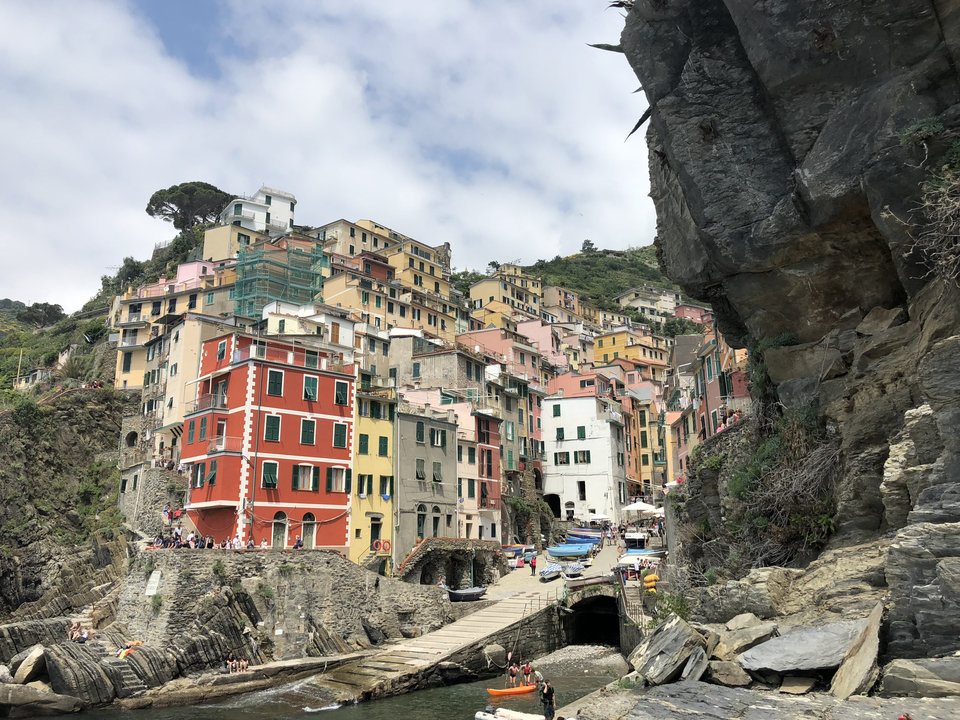 Colorful houses built on a cliffside, with a large rock face and blue sky.