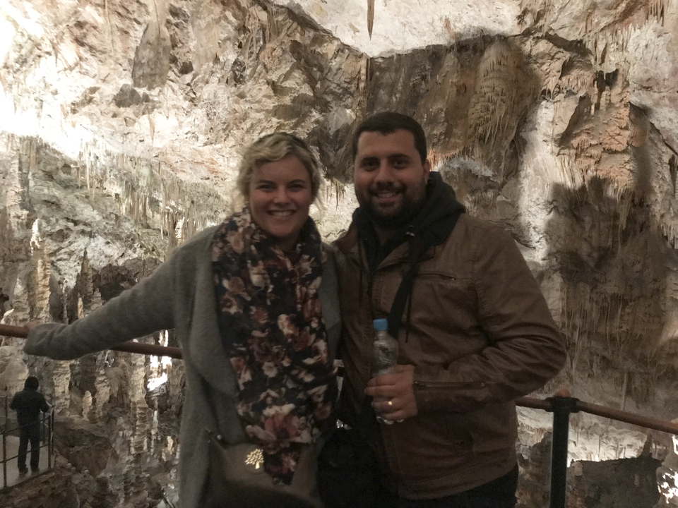 Couple posing inside a cave with stalactites visible above.