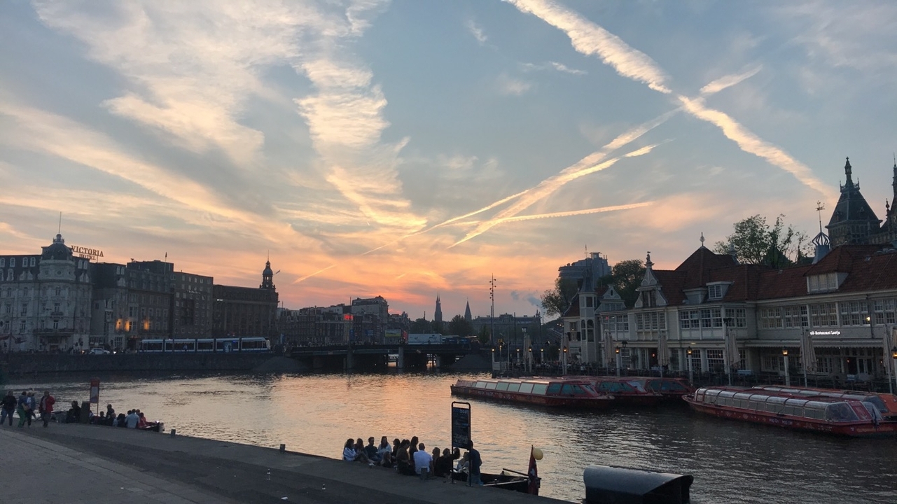 Sunset over a river with historical architecture lining the riverbanks.