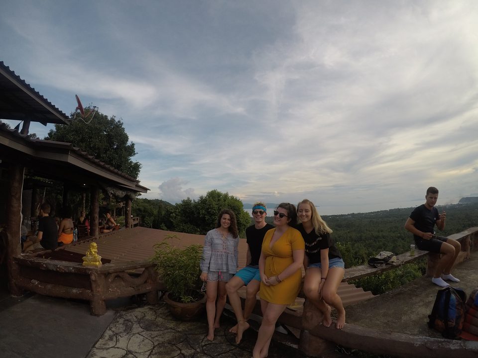 Five people on a deck with a scenic background.