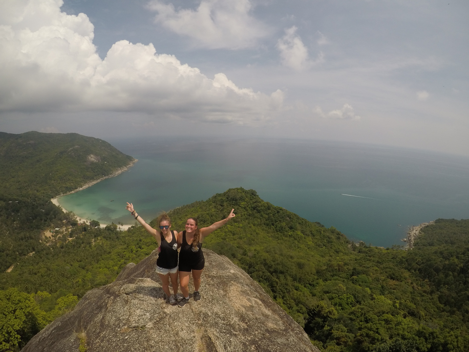 Two women posing on a high vantage point overlooking the sea.