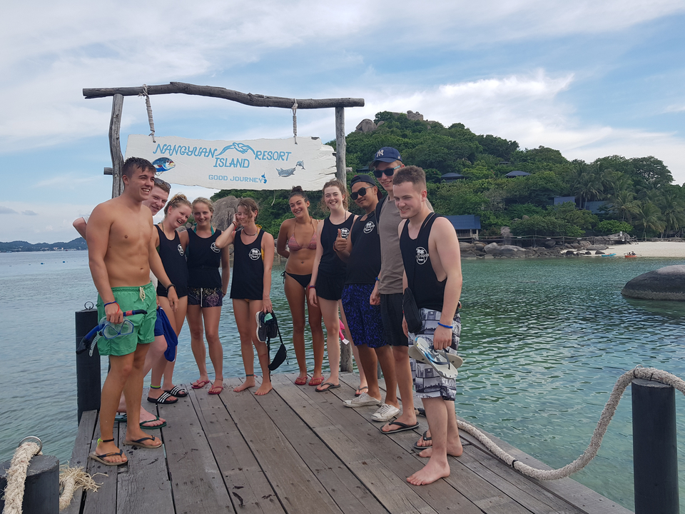 Group of people posing on a dock with a resort sign.