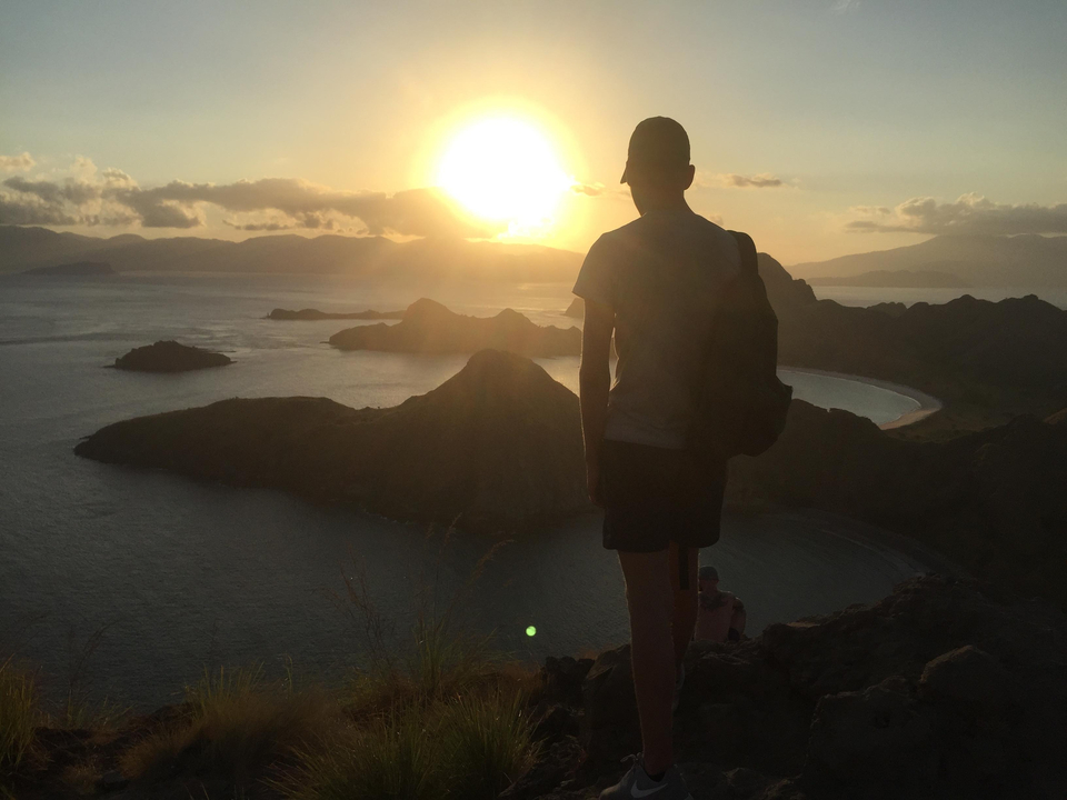 Silhouette of a person with a scenic view of a sunset over hills.