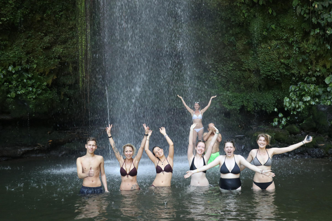 Group of people enjoying a waterfall experience.