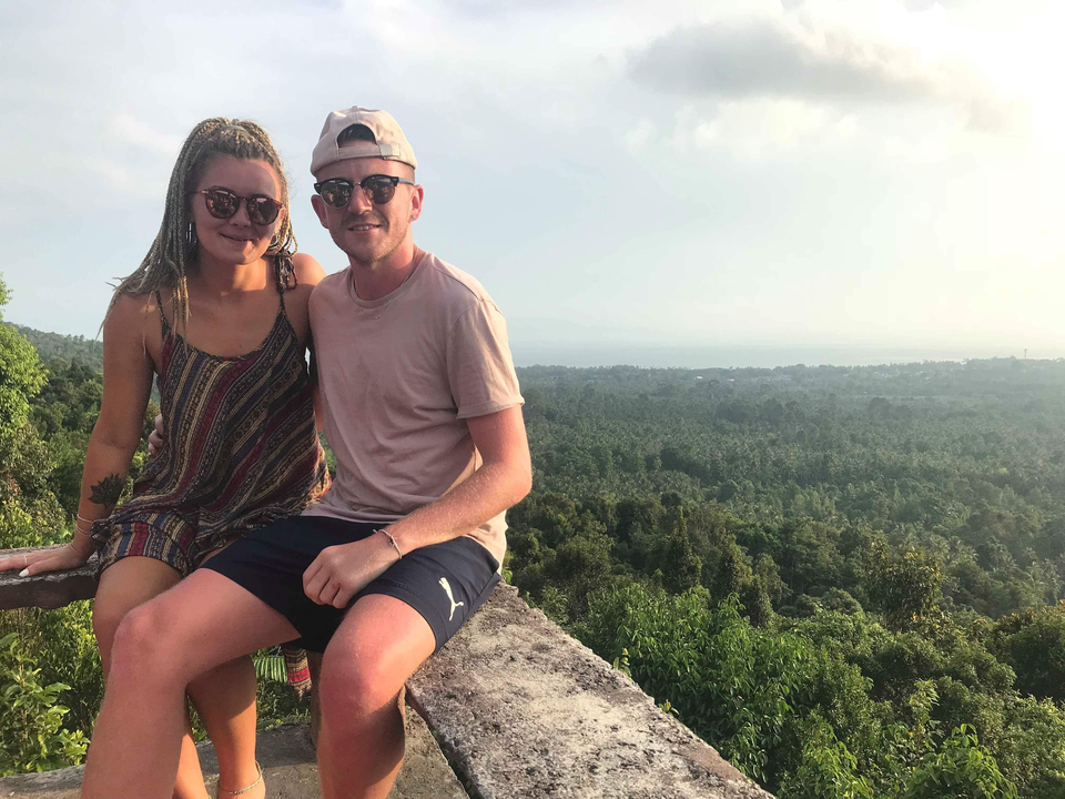 Couple sitting on a ledge with a scenic overlook.