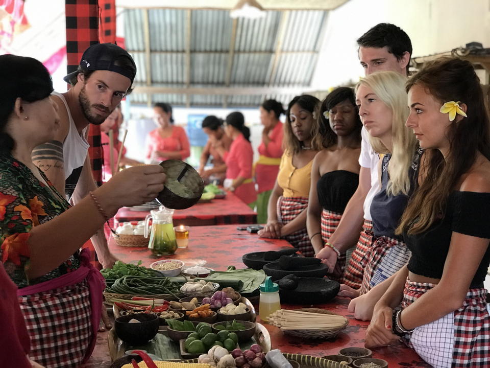 Tourists in a cooking class observing a demonstration.