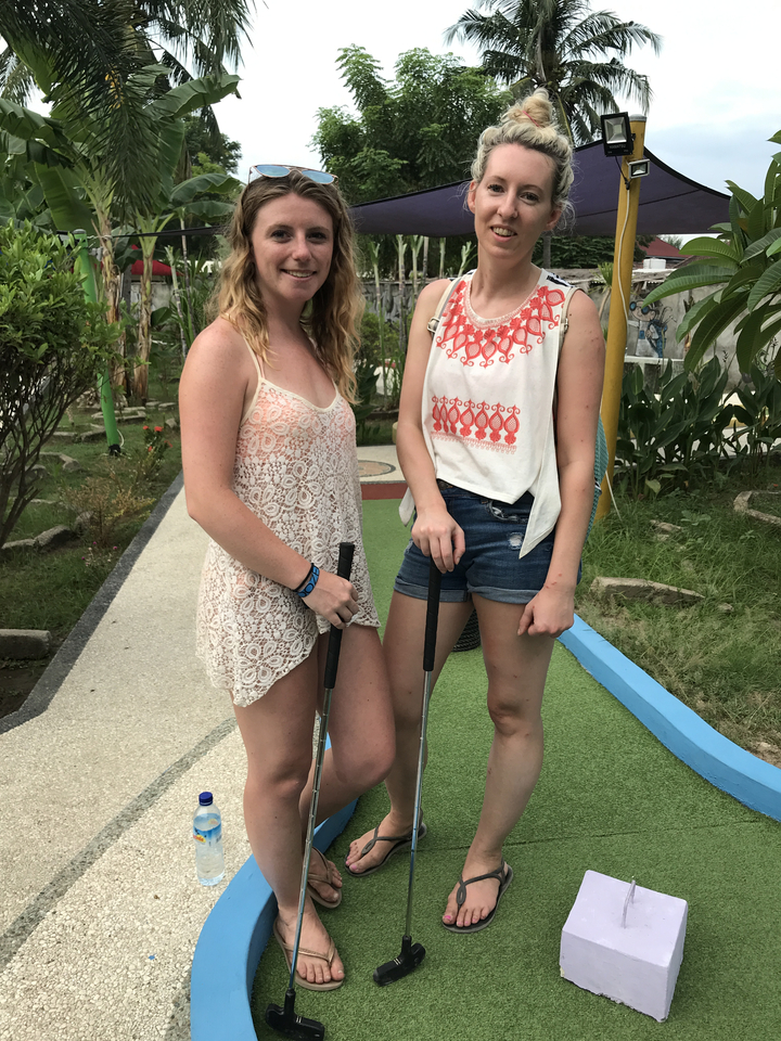 Two women at a mini-golf course posing casually.