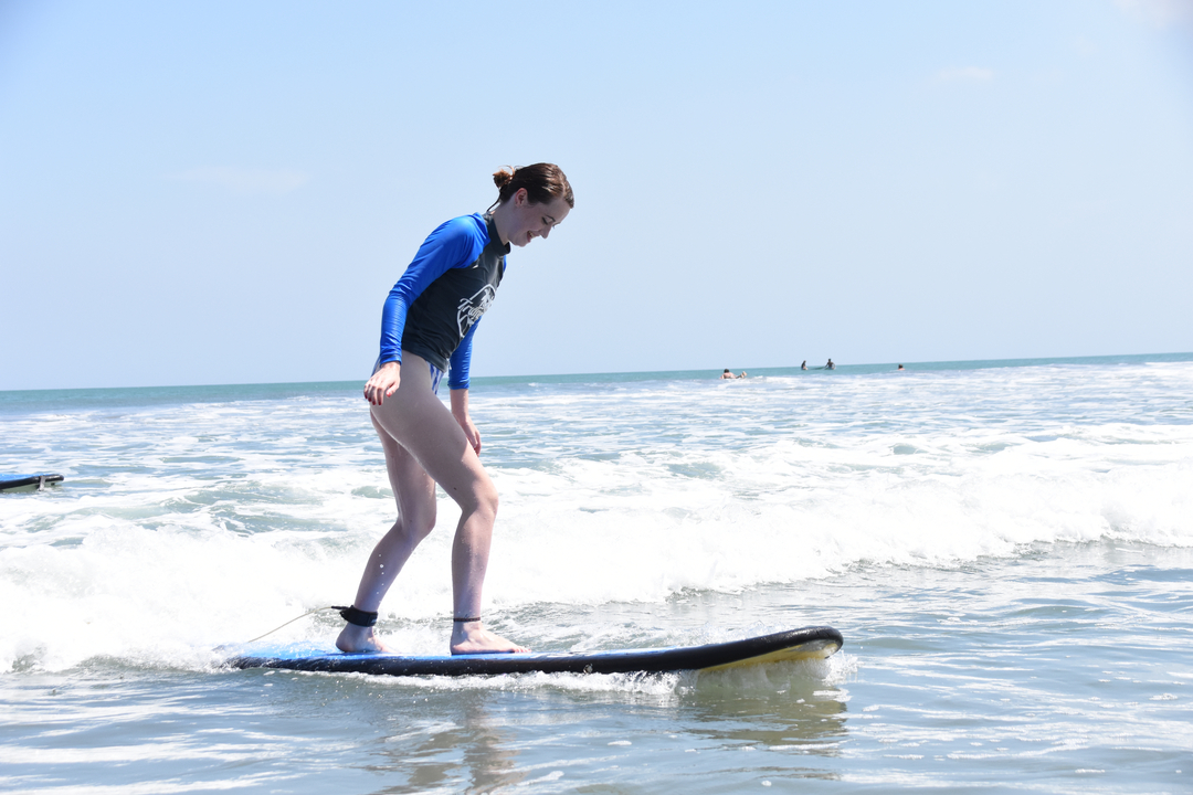 Woman surfing on a beach in bright daylight.