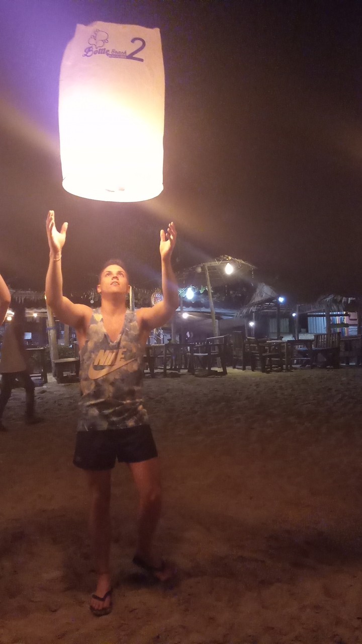 Man raising his arms in a beach setting at night.