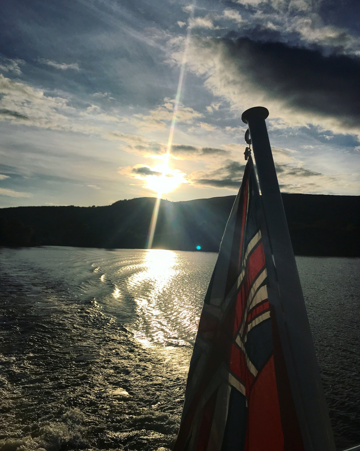 Silhouette of a flag on a boat at sunset
