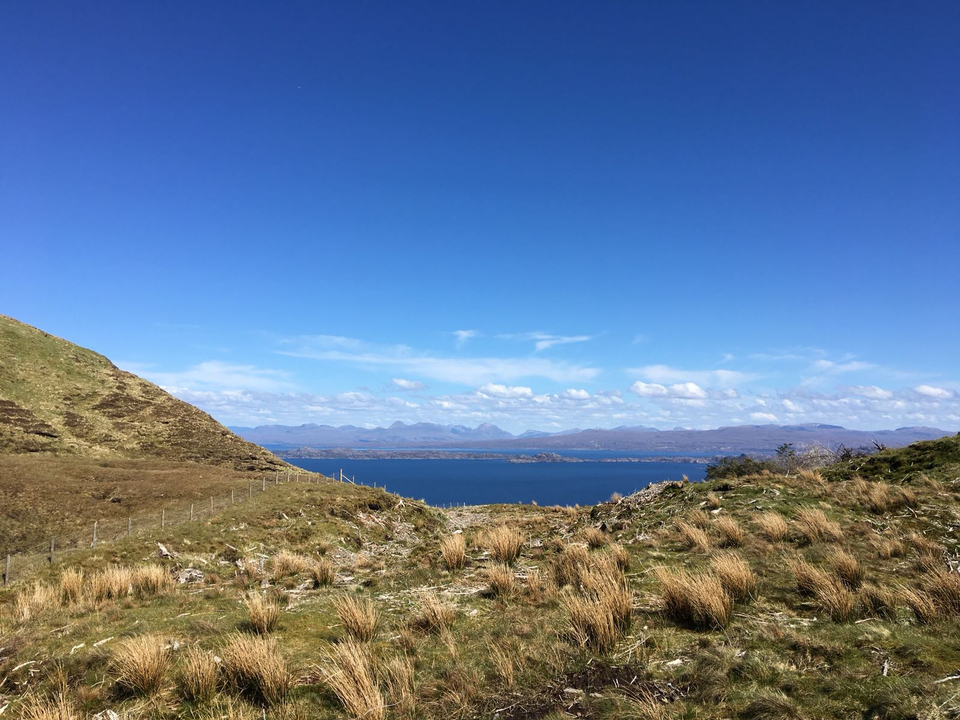 Rolling hills with a view of a lake under a blue sky.