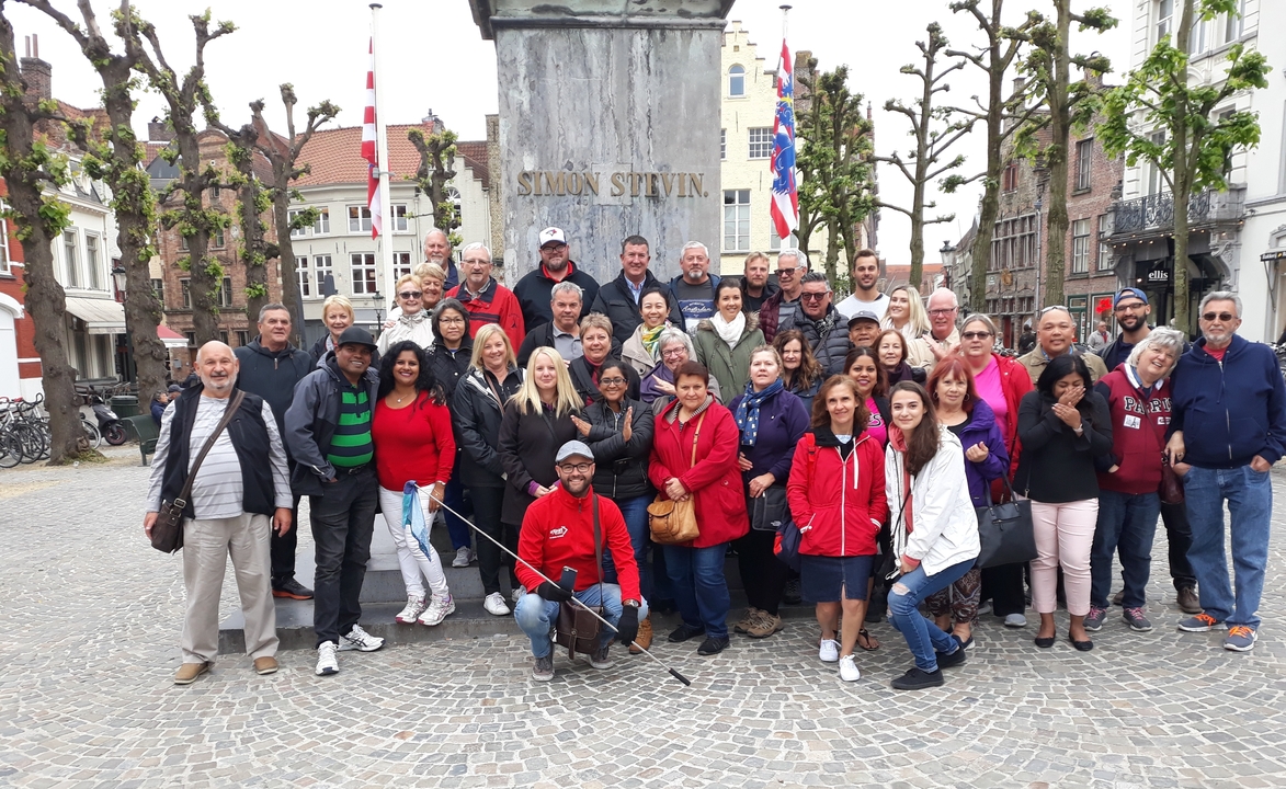 Grand groupe de personnes posant sur une place urbaine.