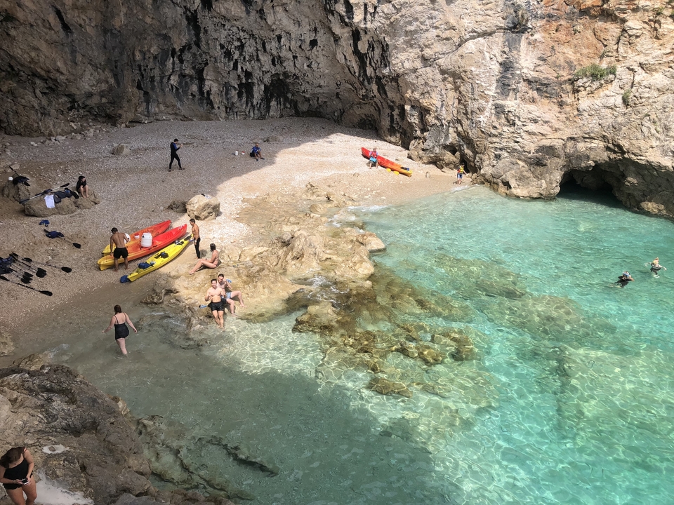 People enjoying a beach with crystal clear water.