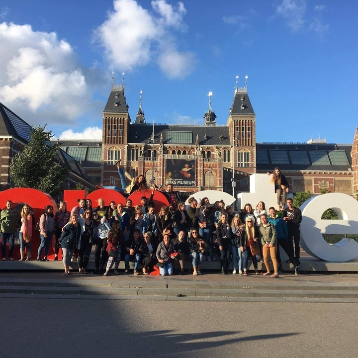 Large group of people posing in front of a museum.