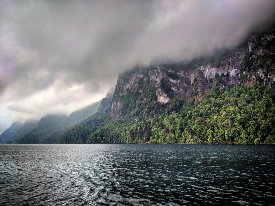 Un paysage brumeux de falaises abruptes et d'un lac.