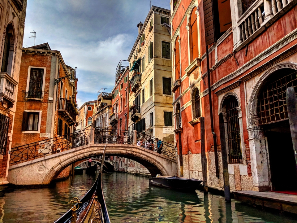 Un canal avec une gondole et un pont entre des bâtiments colorés.
