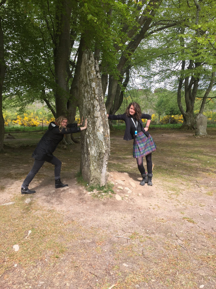People posing near a stone with trees around.