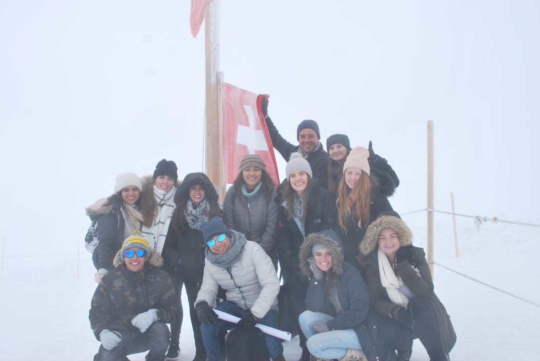 Group of people posing in a snowy environment with a Swiss flag.