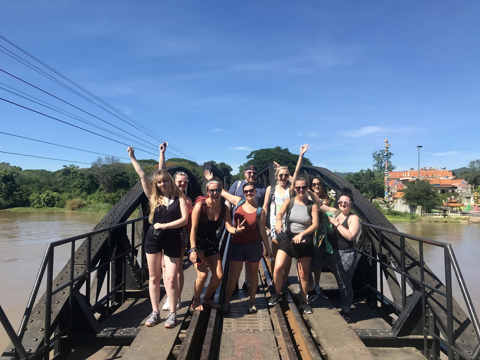 Group of people posing on a bridge.