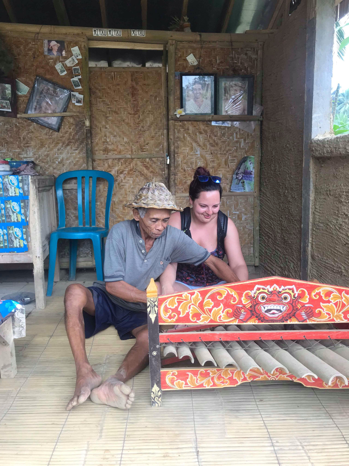 A local artisan working with a tourist on a traditional craft object.