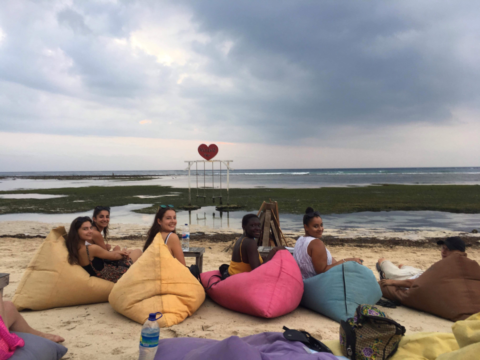 Group of friends relaxing on a beach with beanbags and a view of the sea.