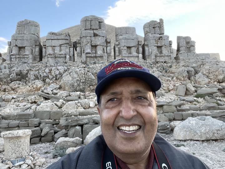 Smiling man in front of ancient stone ruins.