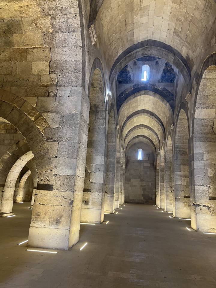 Interior of a stone structure with arches and windows.