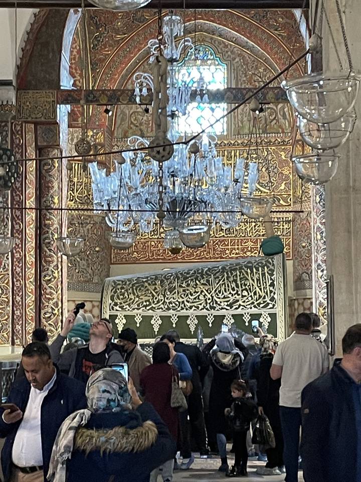 People exploring an ornately decorated interior of a mosque.