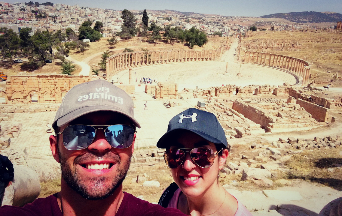 Couple taking a selfie at a historic site with ancient ruins below.