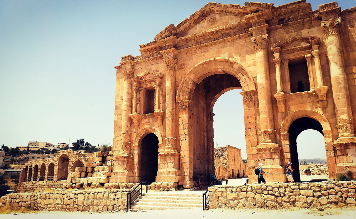 Ancient stone archway with ruins in the background.