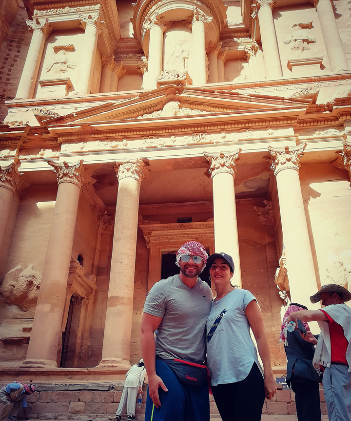 Two people standing in front of the famous Petra Treasury.