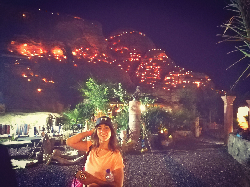 Night view of illuminated rock formations with a young woman in the foreground.